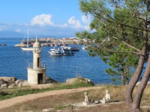 Faro de Punta Moreiras en O Grove, rodeado de vegetación e con vistas al mar.