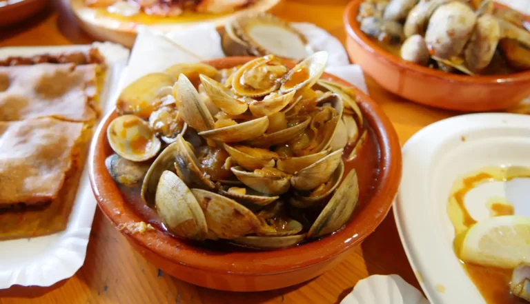 Plato de almejas al ajillo servido en cazuela de barro durante la Fiesta del Marisco en O Grove.