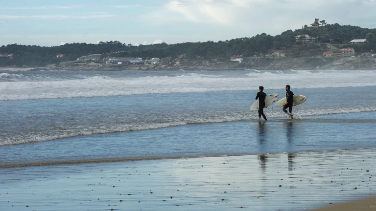 Surfistas entrando al mar en una playa de O Grove