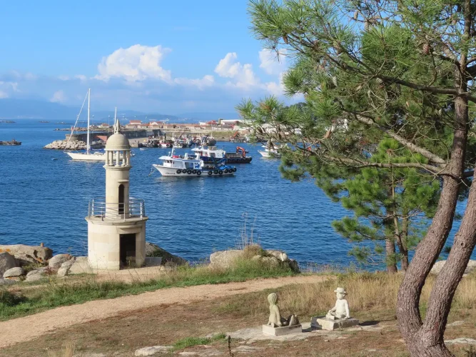 Faro de Punta Moreiras en O Grove, rodeado de vegetación e con vistas al mar.