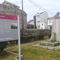 Monumento con estatua de piedra y panel informativo en O Grove