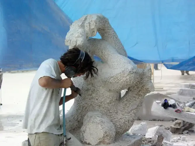 Escultor trabajando en una figura de piedra en O Grove