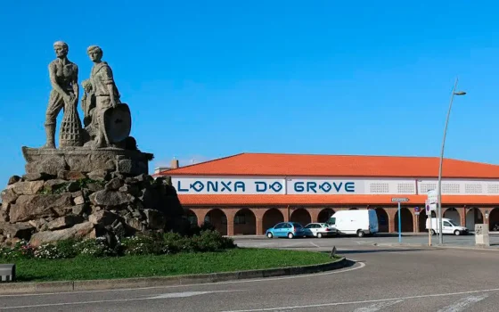 Fachada de la Lonja de O Grove con el monumento a los marineros en primer plano.